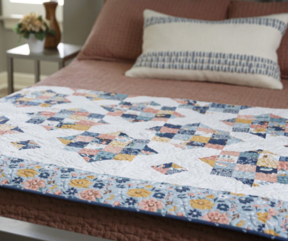 a charm pack quilt folded neatly at the foot of a bed.