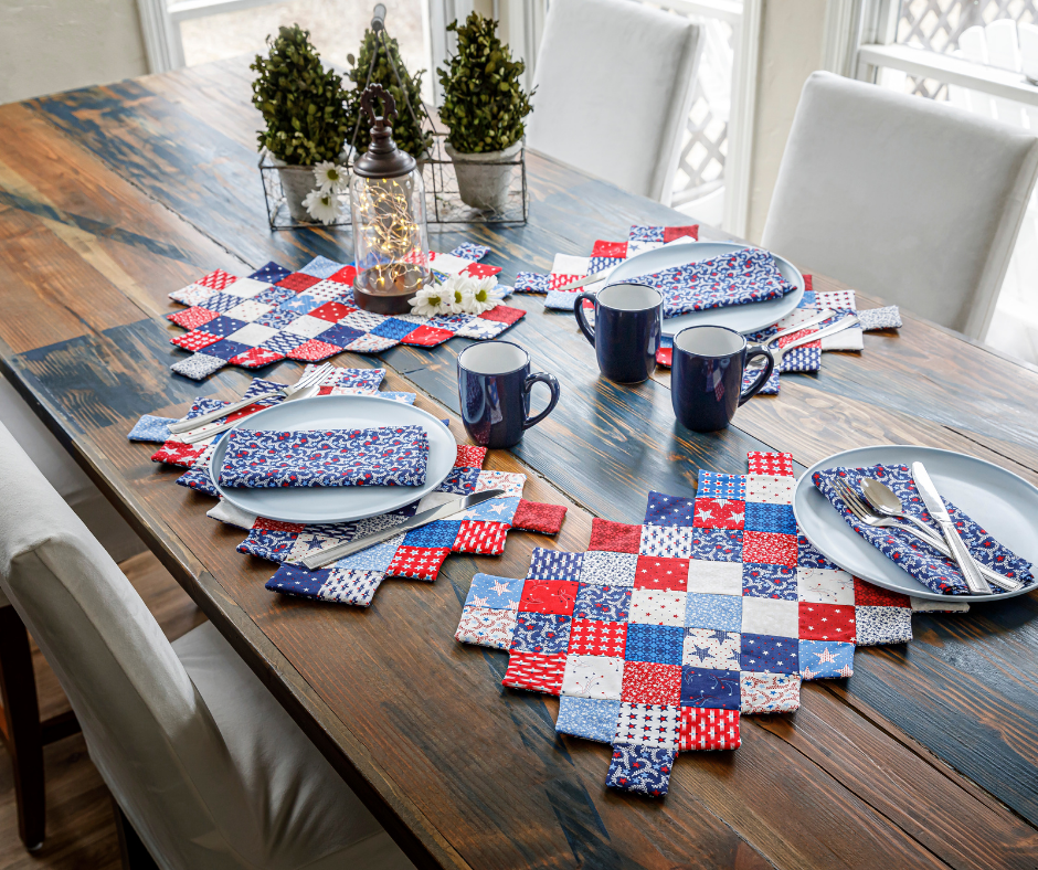 patriotic quilted placemats on a table with dishes and cutlery.