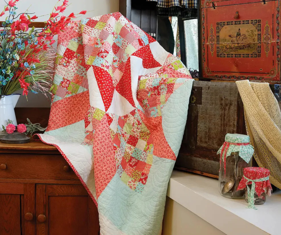 a bright patchwork quilt made with reproduction 1930s fabrics is draped across antique furniture.