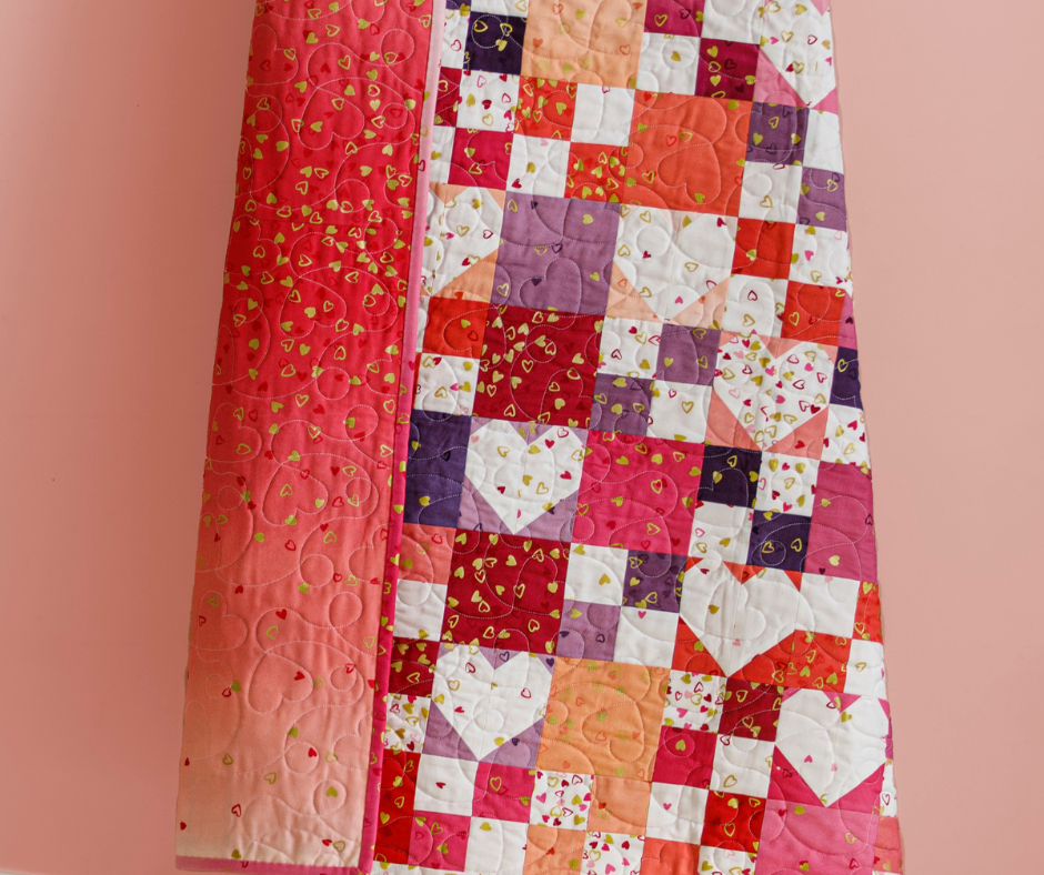 a pink, purple and white quilt with a pretty ombre backing against a light peach background.