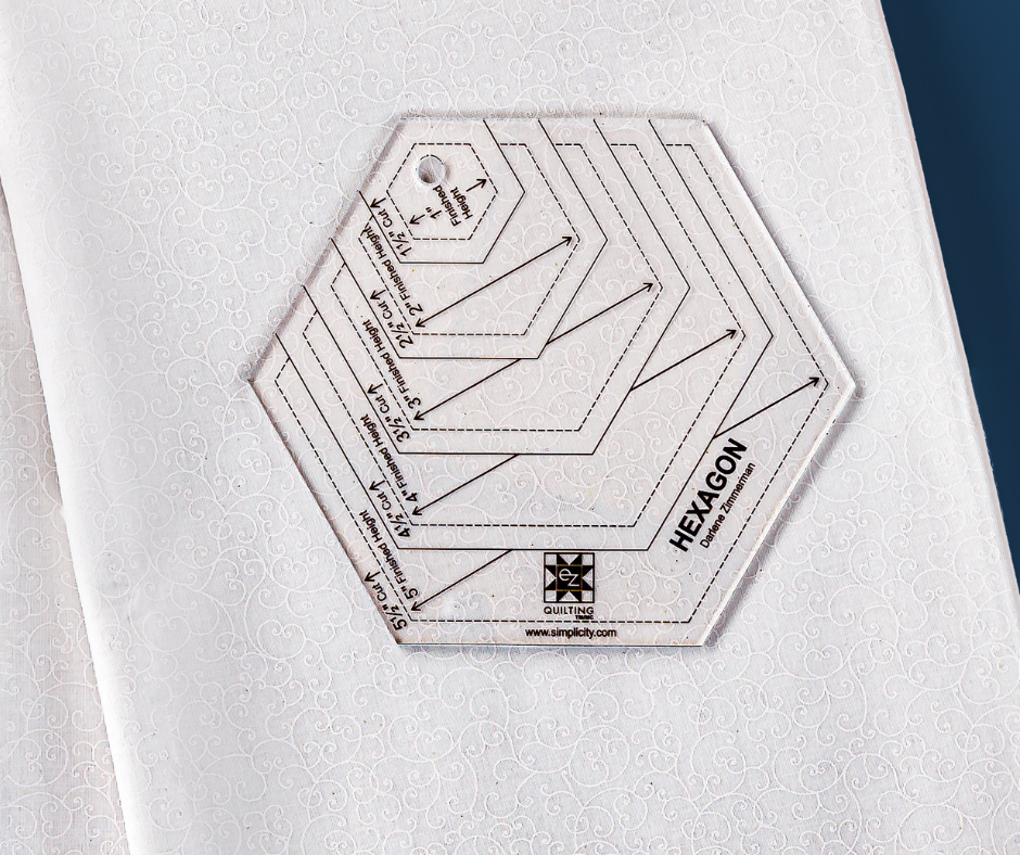 a clear hexagon-shaped quilting ruler laying on top of white fabric with a subtle white print.