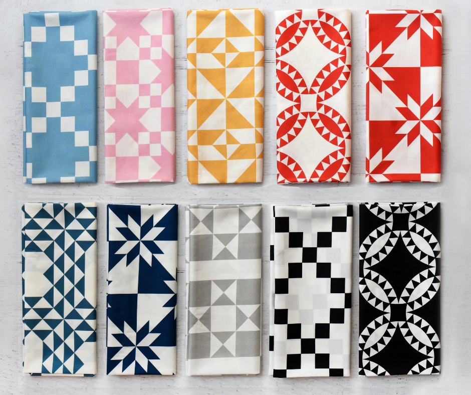 a colorful selection of cheater fabric prints neatly folded and arranged against a light gray background.