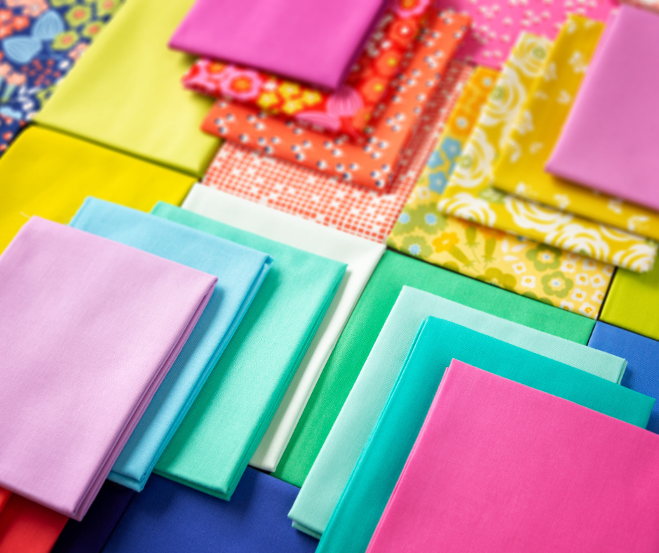 A variety of colorful quilting fabrics neatly folded and arranged.