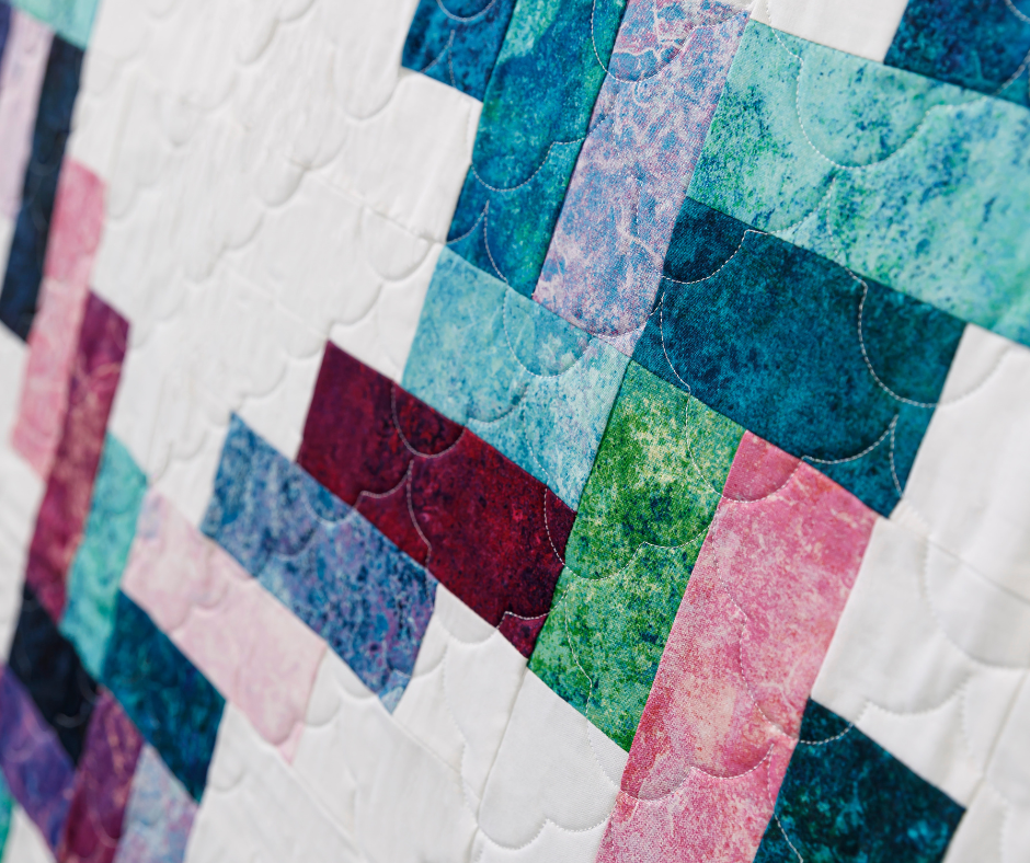 close-up of a quilt made with digitally printed fabrics in a geometric pattern against a white background.