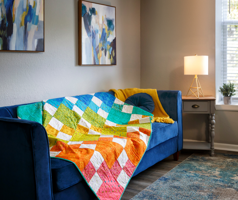 a colorful charm pack quilt draped on a couch.