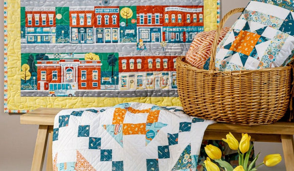 Quilt panel wall hanging with borders, displayed above a finished quilt