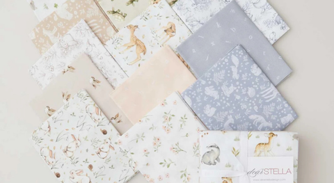 Fat quarter bundle of cotton quilt fabric featuring animals and letters in soft colors.