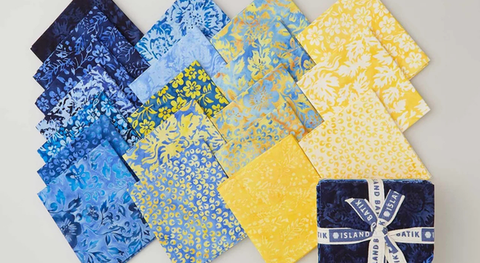 Fat quarter bundle of cotton quilting fabric with batik prints in a yellow and blue palette.