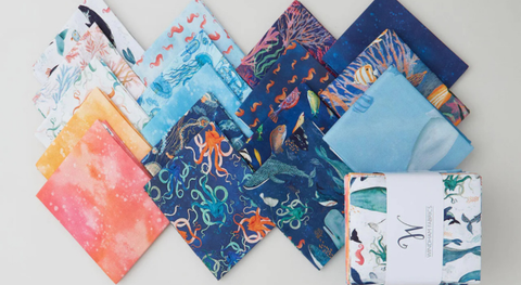 A fat quarter bundle of fabric prints featuring sea creatures in a blue and orange colorway. 