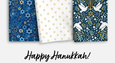 Hanukkah fabric featuring Dreidels, Stars of David, swirls, and leaves arranged on a blue background from the Happy Hanukkah Fabric collection from clothworks.