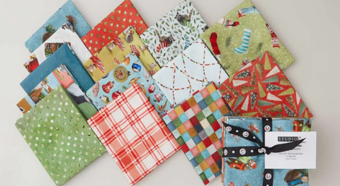Fat quarter bundle of cotton quilt fabric featuring festive woodland animals in a slate, sage, and coral palette.
