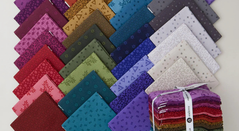 a selection of fat quarter fabrics in a range of jewel tones with subtle prints on them.
