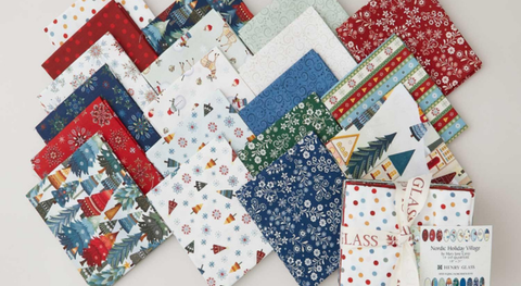 Fat quarter bundle of cotton quilt fabric with a Christmas and winter theme in red, blue, green, and cream.