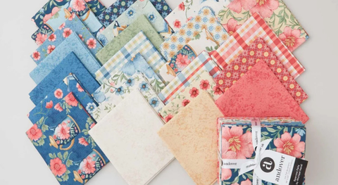Fat quarter bundle of cotton quilting fabric with birds, flowers, teapots, and more in a blue, green, and ivory palette.