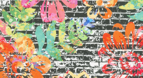 Cotton quilt fabric featuring colorful flowers on a black brick background. 