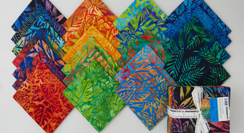 Fat quarters of batiks with tropical foliage in shades of gold, green, blue, and pink. 