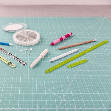 Missouri Star Seam Marker with fabric marking pens, chalk and a seam gauge on a cutting mat